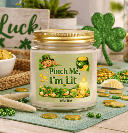 Clear candle jar with a lit candle, green label, and gold lid on with St. Patrick's Day Design and text Pinch Me, I'm Lit that can be personalized.