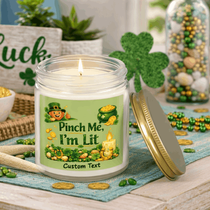 Clear candle jar with a lit candle, green label, and gold lid on with St. Patrick's Day Design and text Pinch Me, I'm Lit that can be personalized.