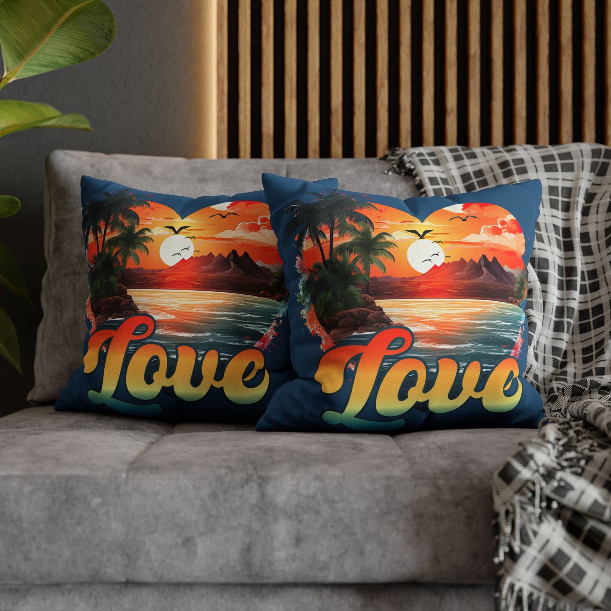Two decorative 18" x 18" blue pillows with a sunset heart design and 'love' text on a gray couch.