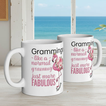 Ceramic coffee mug featuring a flamingo adorned with flowers and the text “Grammingo like a normal Grammy just more fabulous,” available with white, pink, or black handle options.
