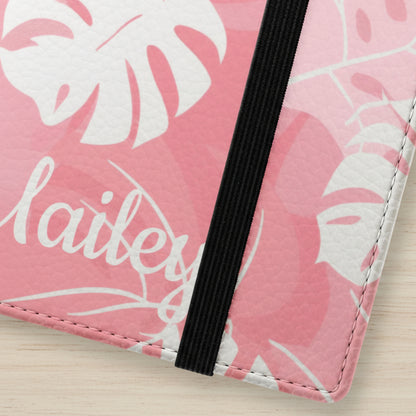 Close-up of a pink flip phone case with white leaf patterns customized with name.