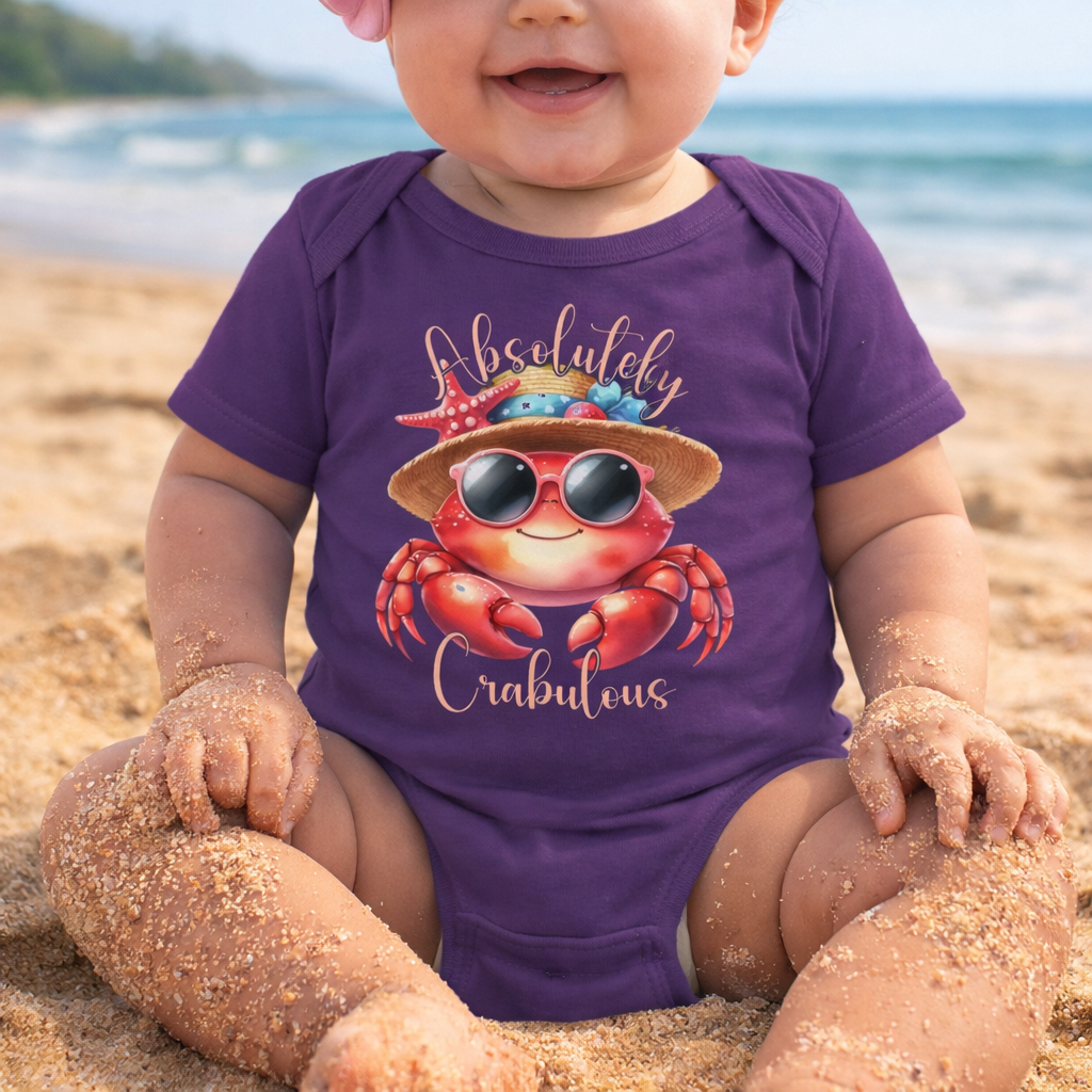 Baby wearing a purple onesie onesie with a crab design and 'Absolutely Crabulous' text on a beach.