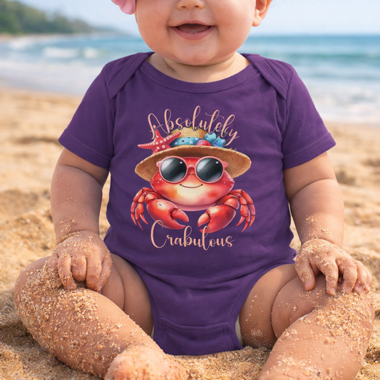 Baby wearing a purple onesie onesie with a crab design and 'Absolutely Crabulous' text on a beach.