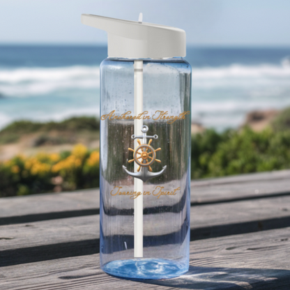 Clear Water bottle with gray lid and straw with an anchor that says anchored in strength and soaring in spirit sitting on a picnic table at the beach