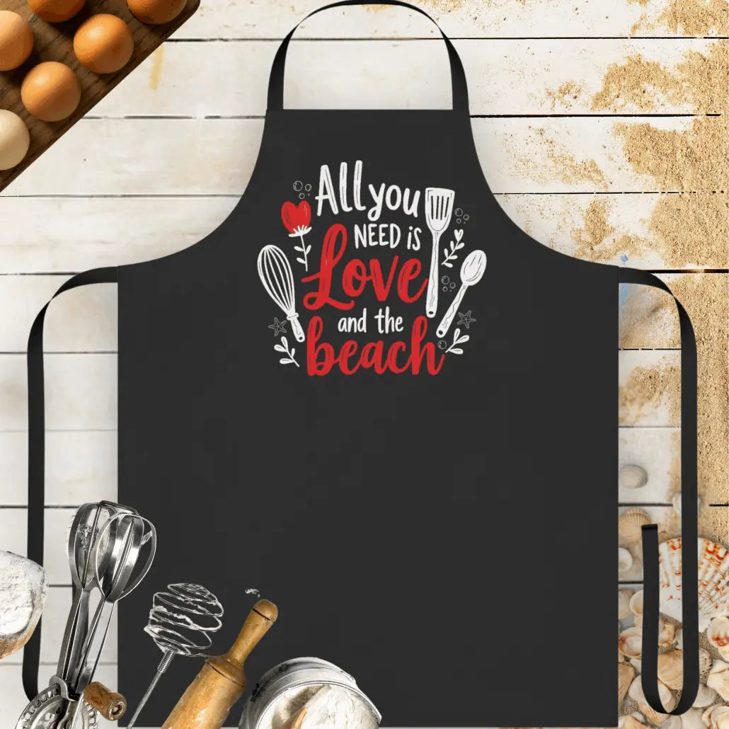 Black Beach-themed apron featuring the phrase 'All You Need is Love and the Beach' with utensil graphics. Made from durable, easy-to-clean fabric, this stylish apron is perfect for cooking, grilling, or beachside barbecues.