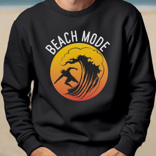 A man standing on the beach in a black crewneck sweatshirt with a Person surfing a wave with a yellow and orange sunset background that says Beach Mode.