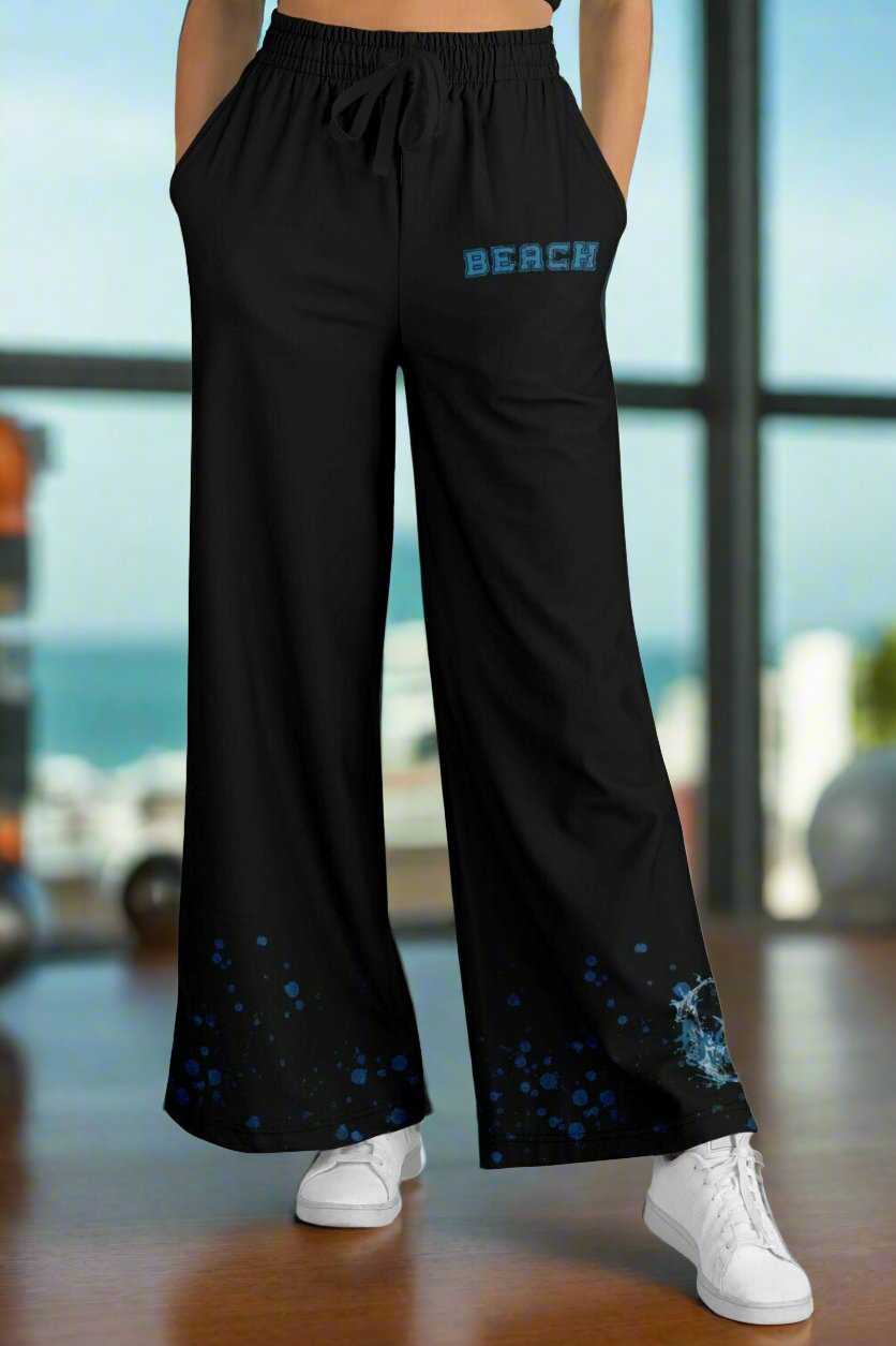 Front of black flare jogger pants with college font Beach on front my left pocket and Beach vibes with wave surrounding and star fish in aqua with aqua bubbles coming up the bottom.