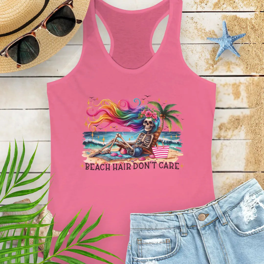 Hot Pink  Racerback Tank Top with a skeleton with rainbow hair flowing in the wind laying on a beach chair at the ocean that says Beach Hair Don't Care.