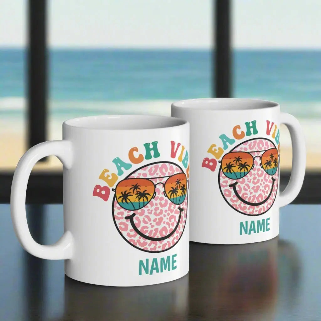 Two White 11 oz ceramic mug with "Beach Vibes" colorful text, featuring a retro smiley face wearing sunset sunglasses with palm trees. Personalized with a name, this coastal-themed coffee mug is perfect for beach lovers and summer vibes.