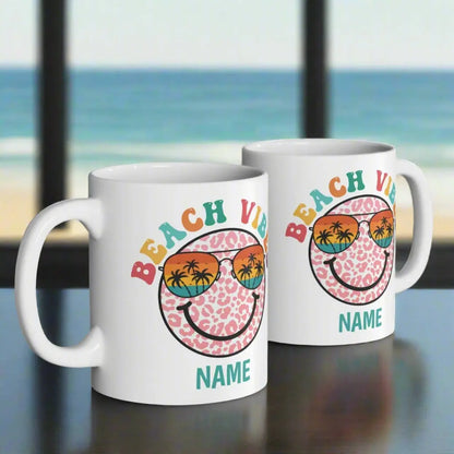 Two White 11 oz ceramic mug with "Beach Vibes" colorful text, featuring a retro smiley face wearing sunset sunglasses with palm trees. Personalized with a name, this coastal-themed coffee mug is perfect for beach lovers and summer vibes.