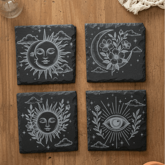 Four black slate coasters with engraved celestial designs.