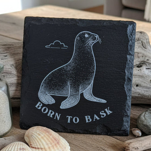 Engraved black slate coaster with seal design and 'Born to Bask' text.