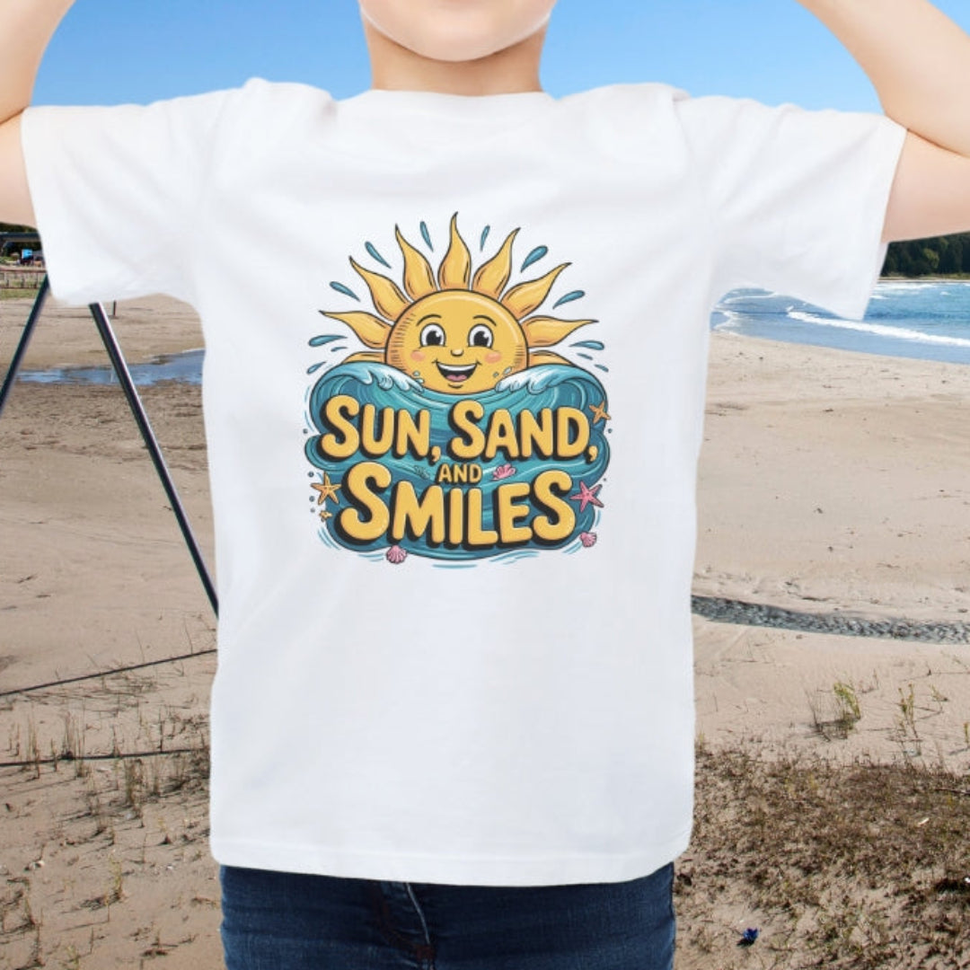 Child wearing a 'Sun, Sand, and Smiles' t-shirt on a beach with a clear blue sky.