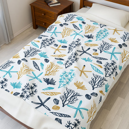 Bed with a colorful coral and starfish patterned comforter in a bedroom setting.
