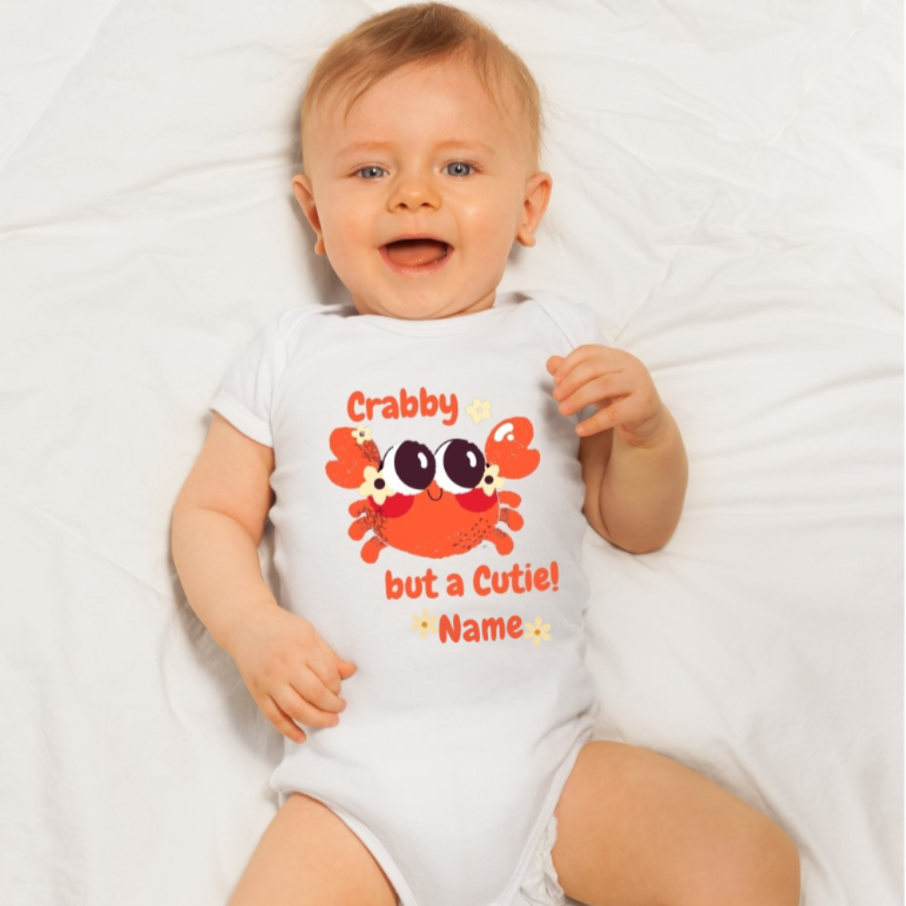 White short sleeved body suit with cartoon crab that says crabby but a cutie with a space for a personalized name below.