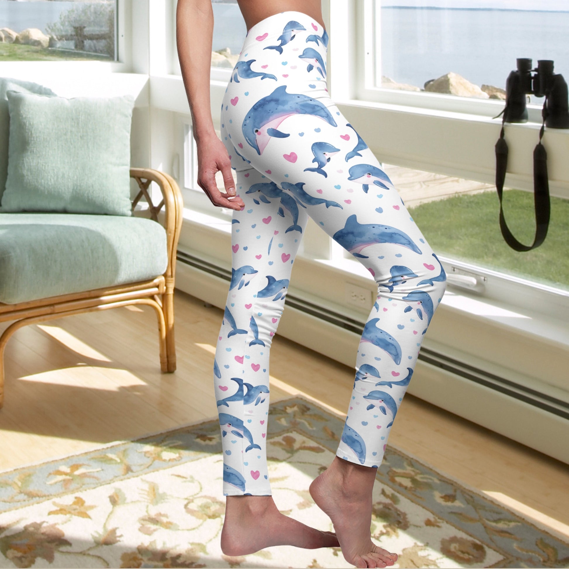 Side view of Woman standing in High Waist Skinny Fit white leggings with pink hearts and blue dolphins.