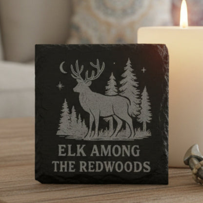 Slate coaster with engraved design of an elk and trees, text 'Elk Among the Redwoods'.