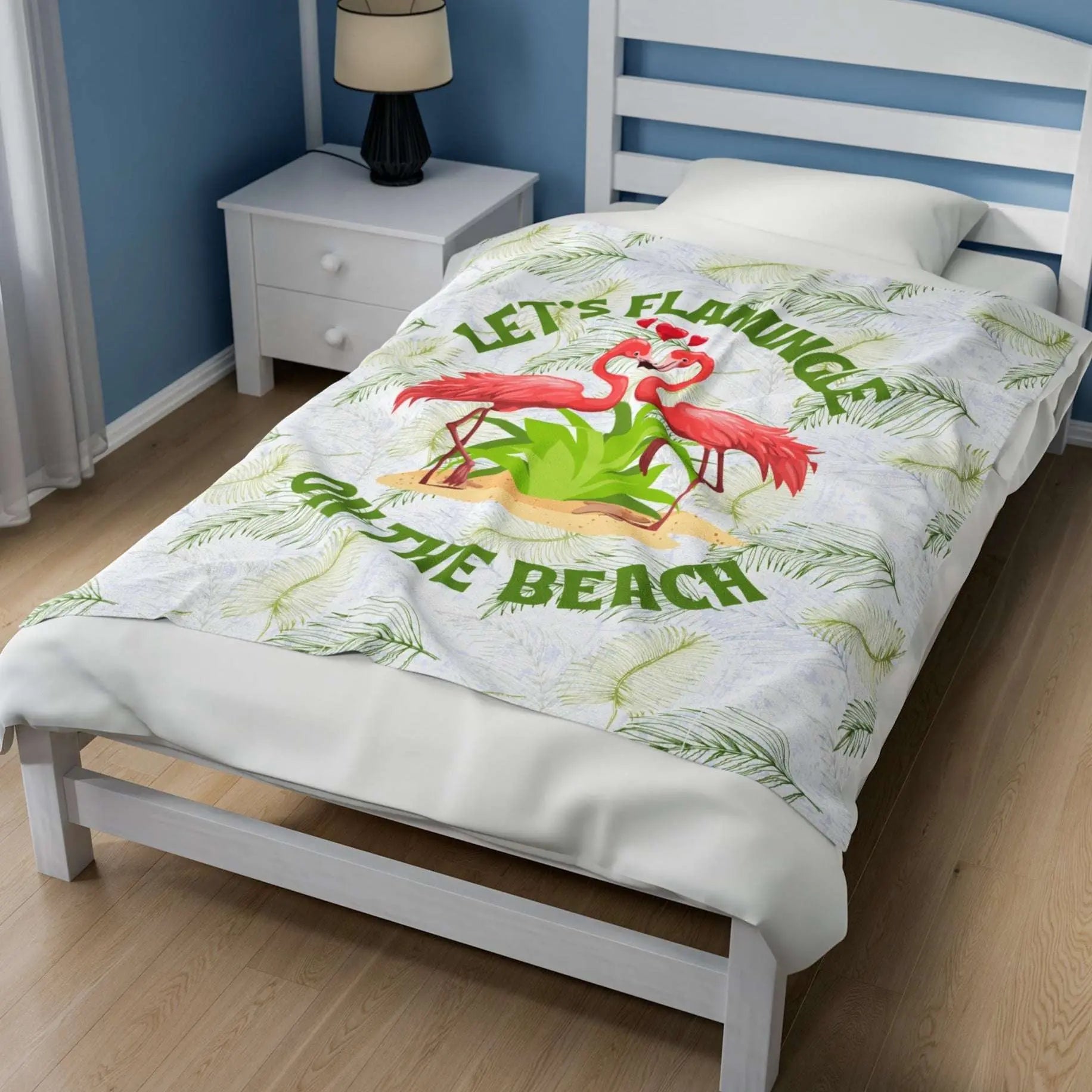 White velveteen plush blanket with green palm fronds and two flamingos in a heart shape that says Let's Flamingle. -perfect for snuggling on cold nights or as a comforting gift for a loved one who is a beach lover.
