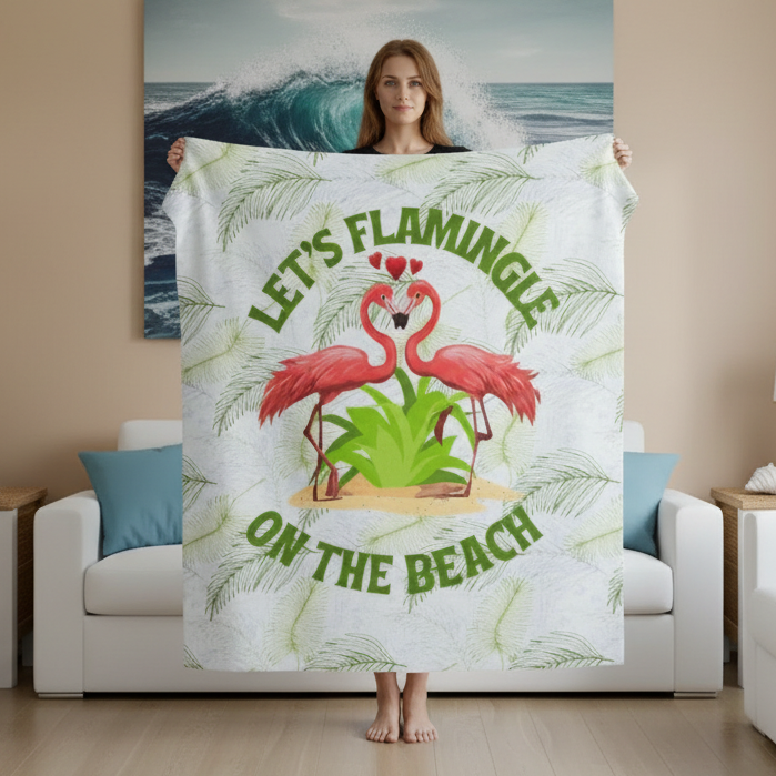 Person holding a blanket with flamingo design and text Lets Flamingle on the Beach in a living room.