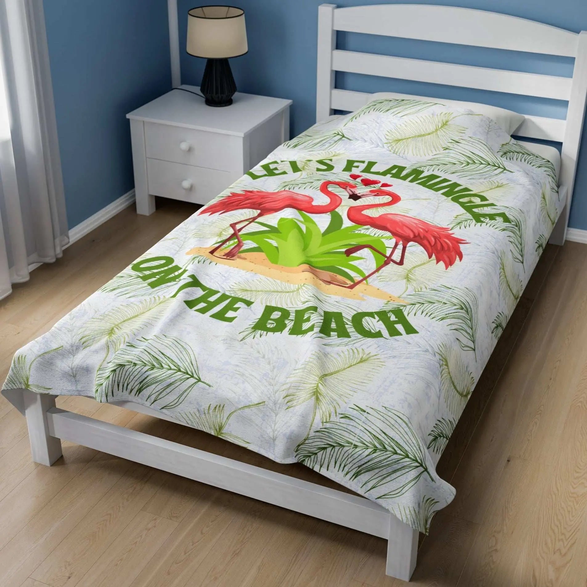 White velveteen plush blanket with green palm fronds and two flamingos in a heart shape that says Let's Flamingle. -perfect for snuggling on cold nights or as a comforting gift for a loved one who is a beach lover.