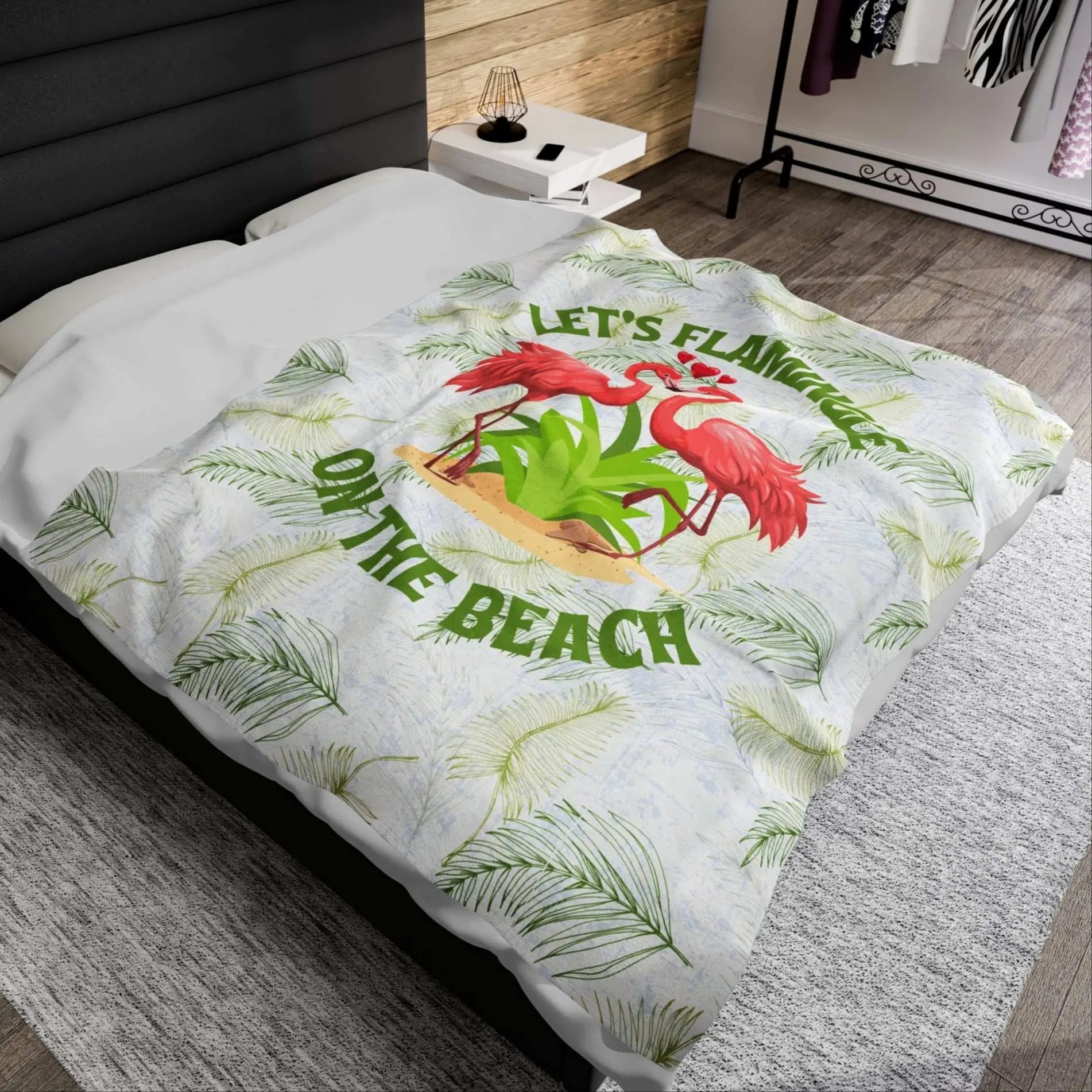 White velveteen plush blanket with green palm fronds and two flamingos in a heart shape that says Let's Flamingle. -perfect for snuggling on cold nights or as a comforting gift for a loved one who is a beach lover.