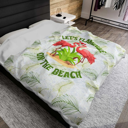White velveteen plush blanket with green palm fronds and two flamingos in a heart shape that says Let's Flamingle. -perfect for snuggling on cold nights or as a comforting gift for a loved one who is a beach lover.