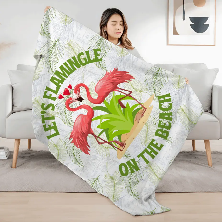 White velveteen plush blanket with green palm fronds and two flamingos in a heart shape that says Let's Flamingle. -perfect for snuggling on cold nights or as a comforting gift for a loved one who is a beach lover.