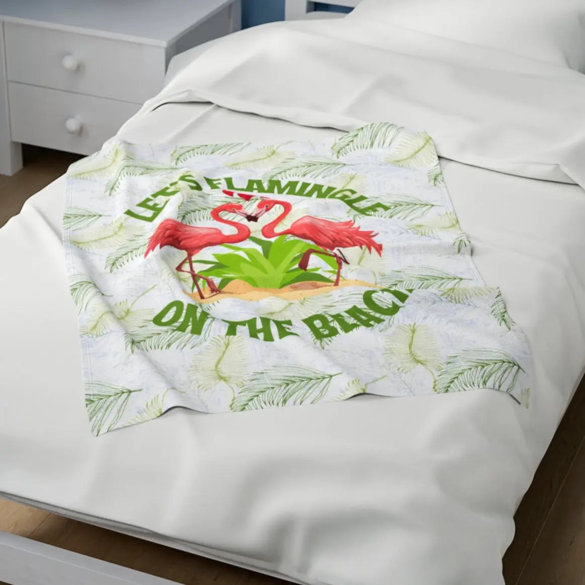 White velveteen plush blanket with green palm fronds and two flamingos in a heart shape that says Let's Flamingle. -perfect for snuggling on cold nights or as a comforting gift for a loved one who is a beach lover.