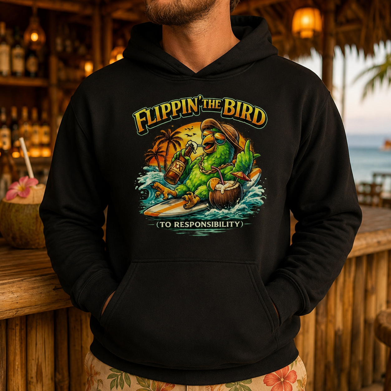 A man wearing a black pullover hoodie with a colorful retro graphic of a green parrot surfing on a wave, with the text 'FLIPPIN' THE BIRD (TO RESPONSIBILITY)'. The background depicts a warm, blurred tropical beach bar setting.