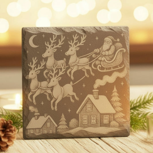 Decorative stone with engraved Christmas scene featuring Santa and reindeer, set against a warm, blurred light background.
