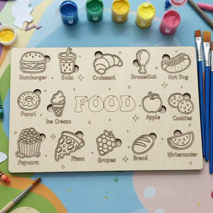 A wooden puzzle board engraved with food illustrations including a hamburger, soda, croissant, drumstick, hot dog, donut, ice cream, apple, cookies, popcorn, pizza, grapes, bread, and watermelon.