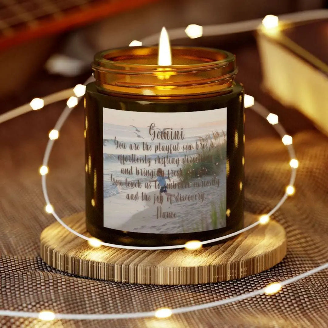 Elegant Gemini Zodiac hand-poured coconut apricot wax scented candle in a 4 oz amber glass jar, featuring a scene of crashing waves with a man in the distance on a rock with the bright sun shining off of the waves girl running  on the beach to the ocean water and an inspirational quote personalized. A beach-inspired astrology gift, perfect for relaxation and decor.