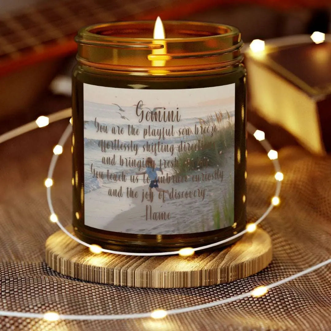 Elegant Gemini Zodiac hand-poured coconut apricot wax scented candle in a 9 oz amber glass jar, featuring a scene of crashing waves with a man in the distance on a rock with the bright sun shining off of the waves girl running  on the beach to the ocean water and an inspirational quote personalized. A beach-inspired astrology gift, perfect for relaxation and decor.