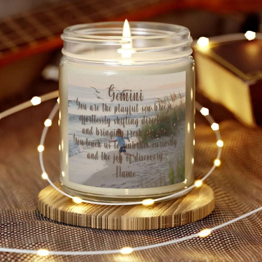 Elegant Gemini Zodiac hand-poured coconut apricot wax scented candle in a 9 oz clear glass jar, featuring a scene of crashing waves with a man in the distance on a rock with the bright sun shining off of the waves girl running  on the beach to the ocean water and an inspirational quote personalized. A beach-inspired astrology gift, perfect for relaxation and decor.