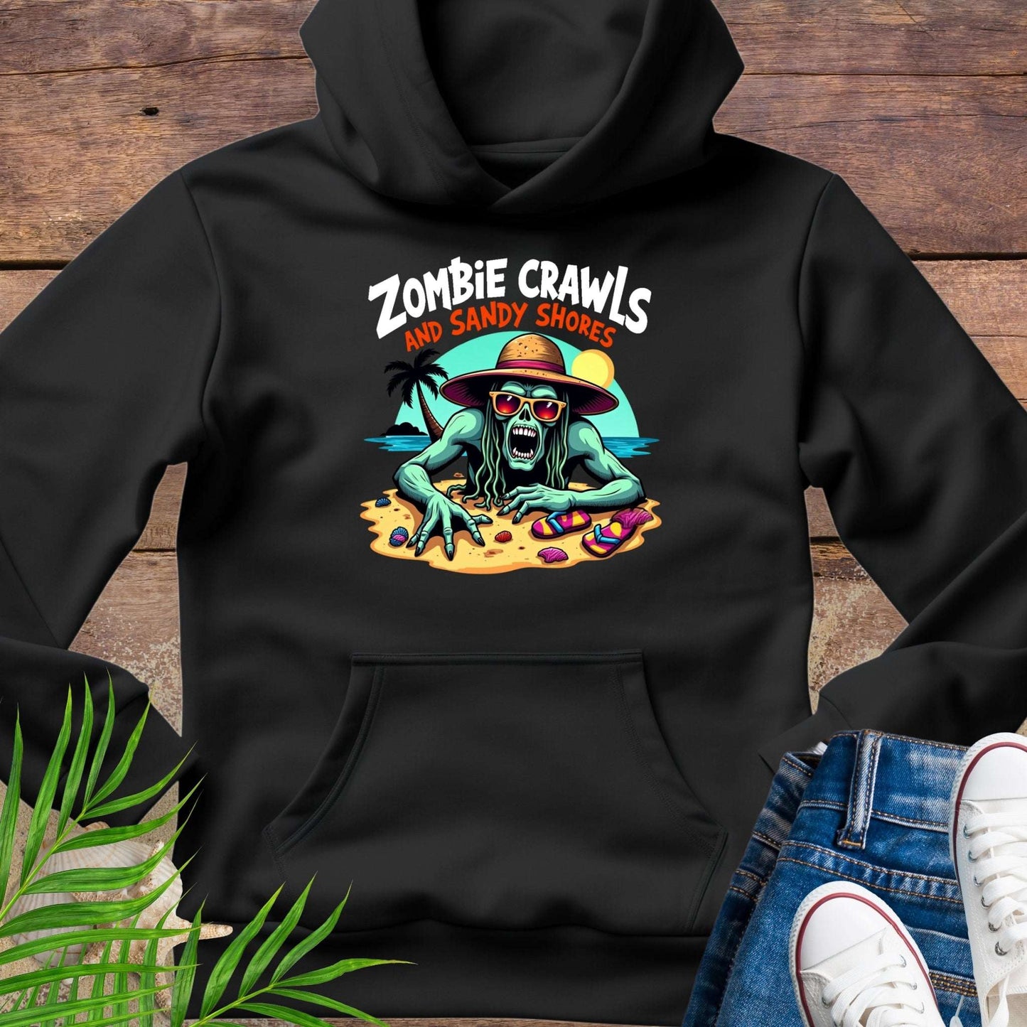 Black hoodie with a graphic design of a zombie on sandy shores, placed on a wooden surface.