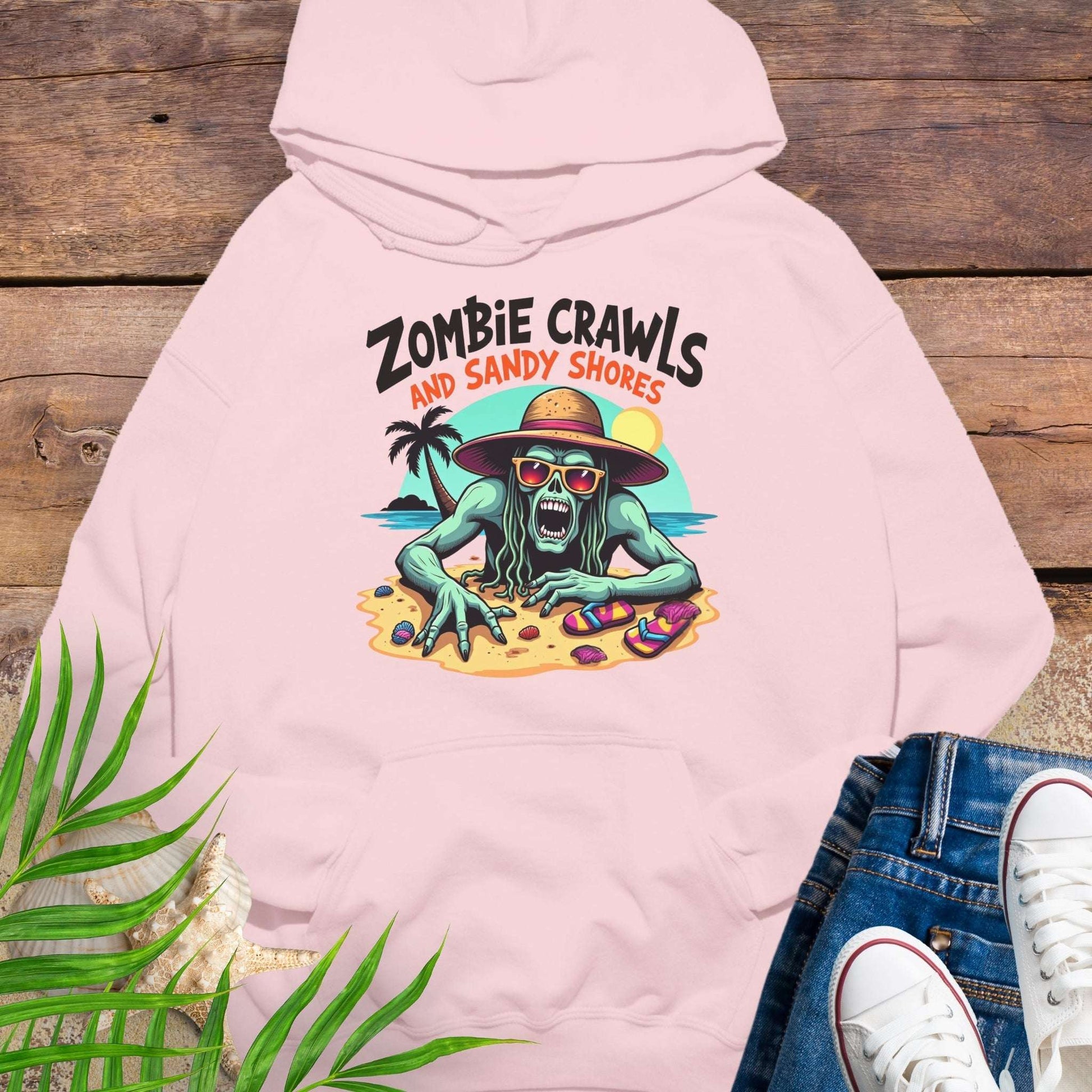 Pink hoodie with zombie graphic and text 'Zombie Crawls and Sandy Shores' on a wooden surface.