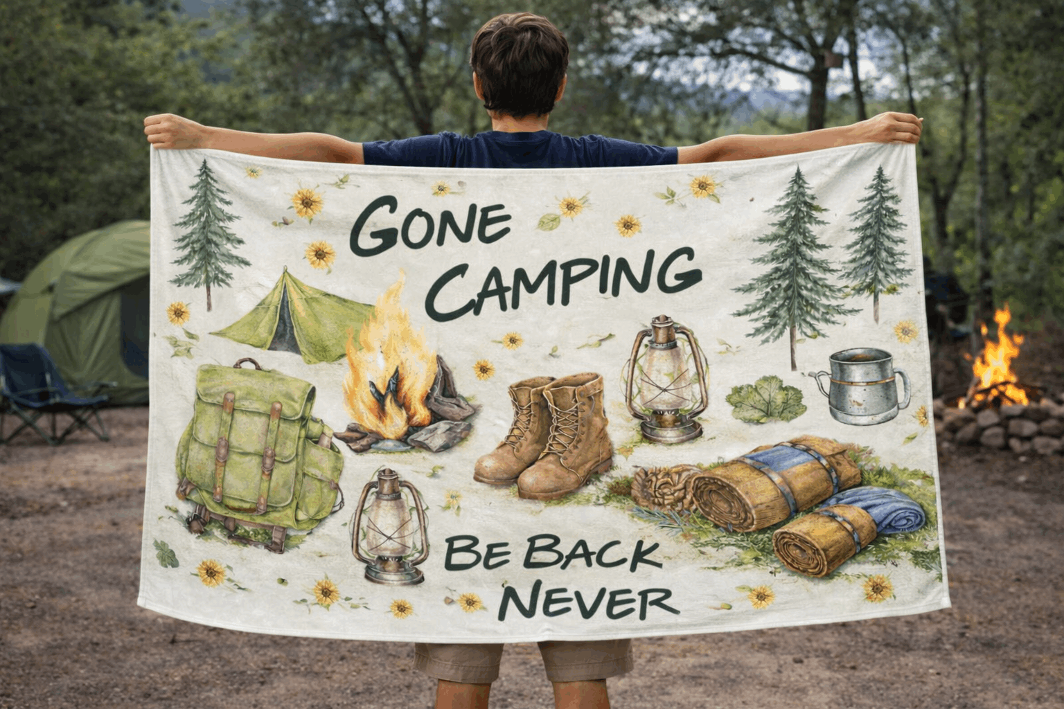 Person holding a 'Gone Camping' beach towel with camping-themed illustrations in a forest setting.