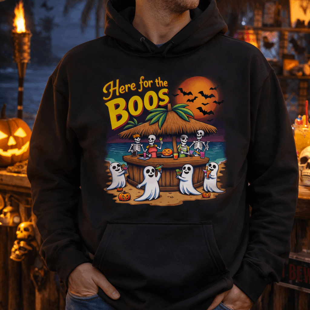 Person wearing a black hoodie with a Halloween-themed design featuring skeletons and ghosts at a beach bar.