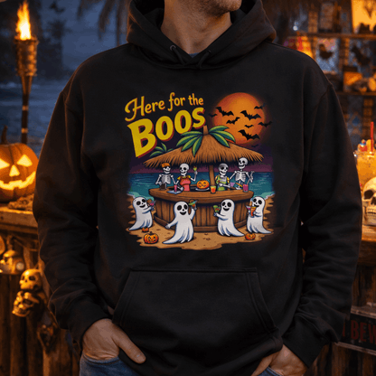 Person wearing a black hoodie with a Halloween-themed design featuring skeletons and ghosts at a beach bar.