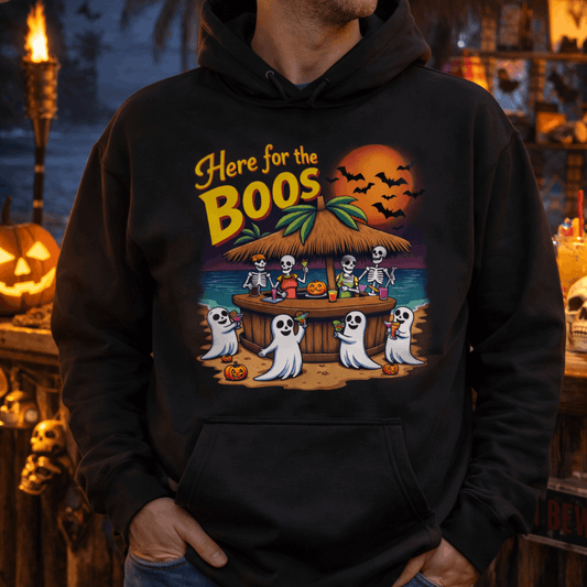Person wearing a black hoodie with a Halloween-themed design featuring skeletons and ghosts at a beach bar.