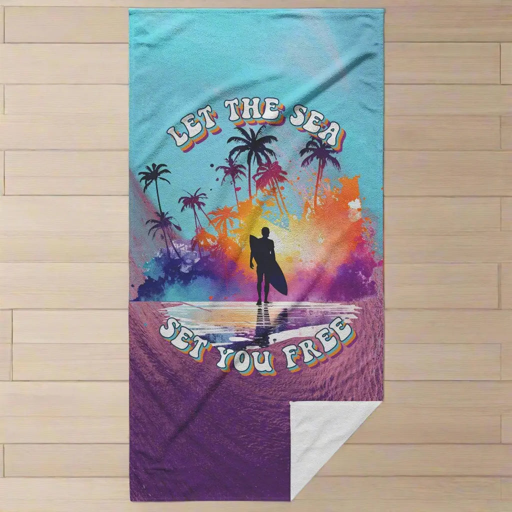a beach towel that has a purple wave and blue sky with the words Let the Sea Set You Free