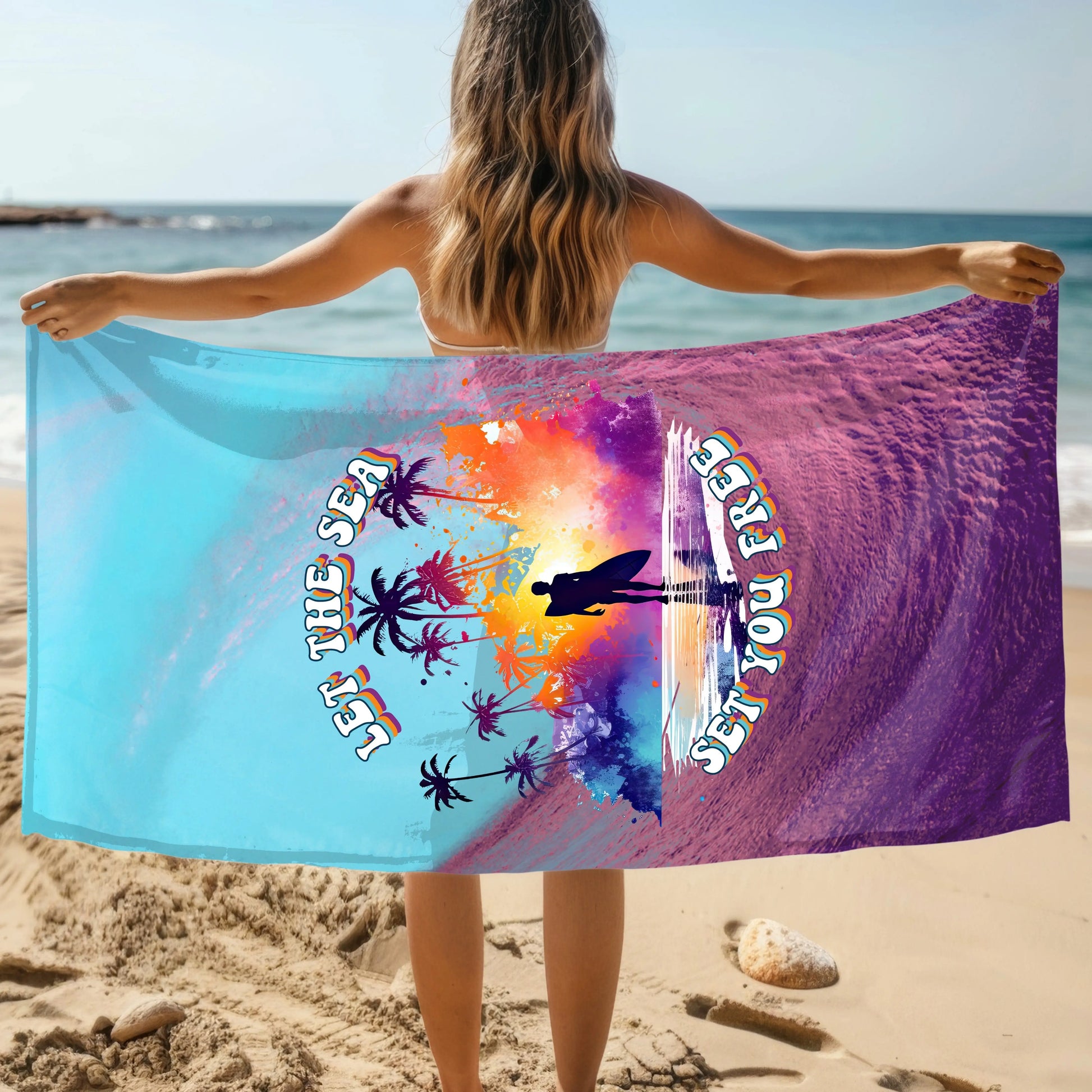 Woman holding a beach towel that has a purple wave and blue sky with the words Let the Sea Set You Free