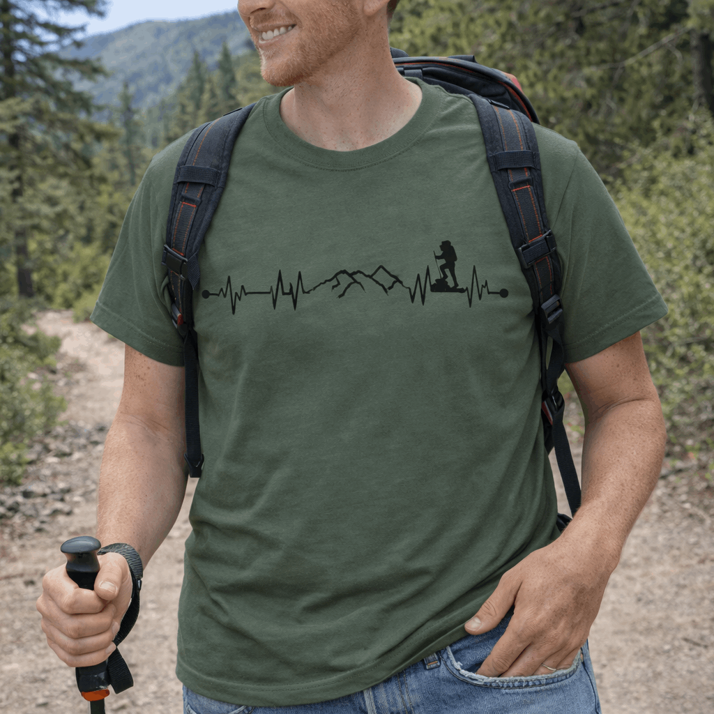 Man hiking in a forest wearing a green t-shirt with a heartline design with a mountain and backpacker.