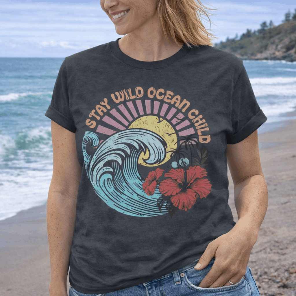 Person wearing a t-shirt with a wave and hibiscus design that says Stay Wild Ocean Child.