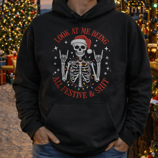 Person wearing a black hoodie with a festive skeleton design in a Christmas-themed setting.