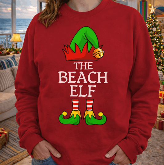 Person wearing a red 'The Beach Elf' sweatshirt in a festive indoor setting.