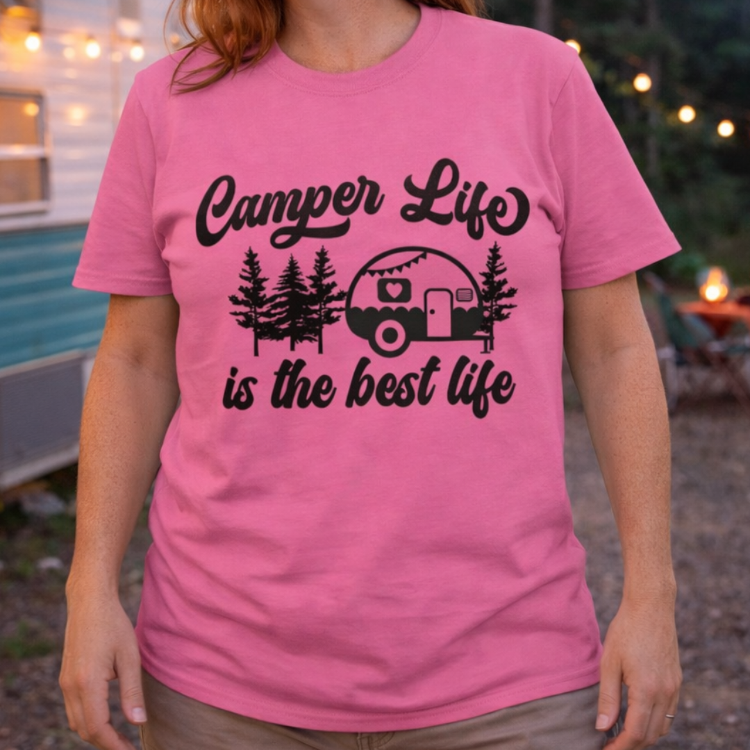 Person wearing a pink t-shirt with 'Camper Life is the best life' text in front of a camper.