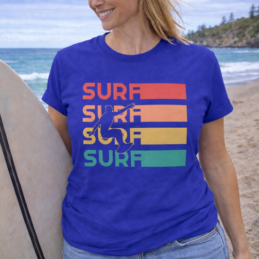 Person wearing a blue t-shirt with 'SURF' retro sunset text on a beach. 