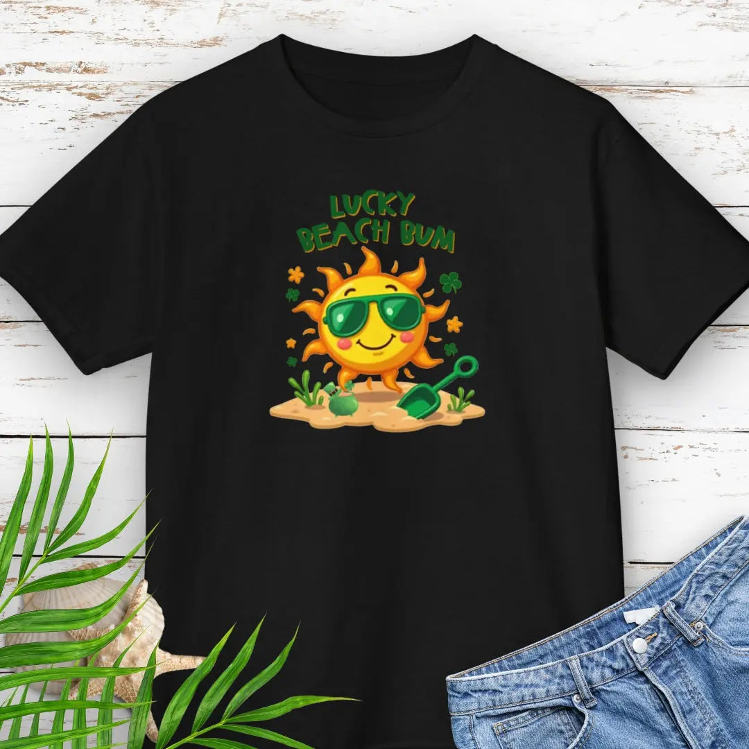 Lucky Beach Bum Child's Black T-shirt with a smiling sun wearing green sunglasses on the beach with beach toys.