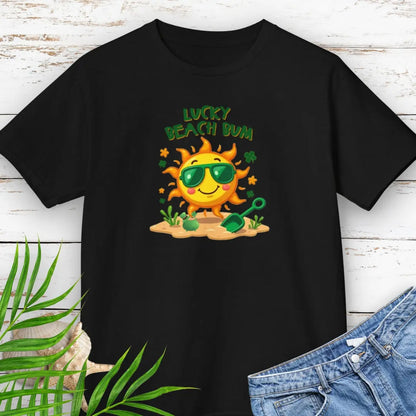 Lucky Beach Bum Child's Black T-shirt with a smiling sun wearing green sunglasses on the beach with beach toys.
